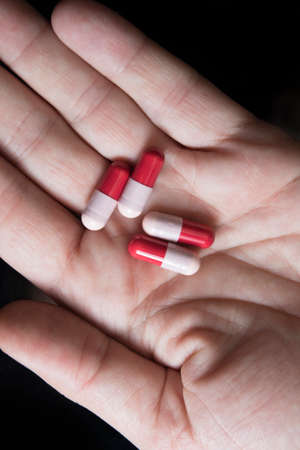 Four red and pink  antibiotic capsule on man handの写真素材