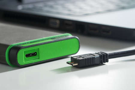 Green external hard disk with cable on whiteの写真素材