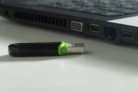 Black and green UBS flash drive and  laptop