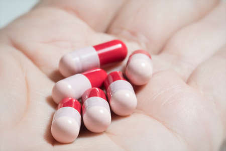 Red and pink antibiotics capsule on palmの写真素材