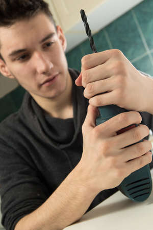 Young worker changing drill bits to drilling machineの写真素材