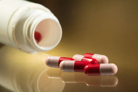 Red and pink antibiotics capsule on golden background