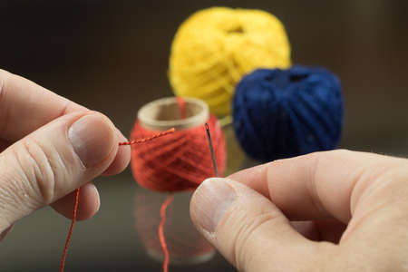 Tailor fingers is  threading a needle 