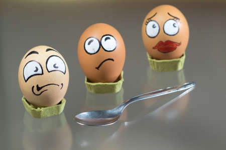 Three frightened egg faces and metal spoonの写真素材