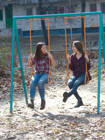 Two young girl friend at the swingsの写真素材