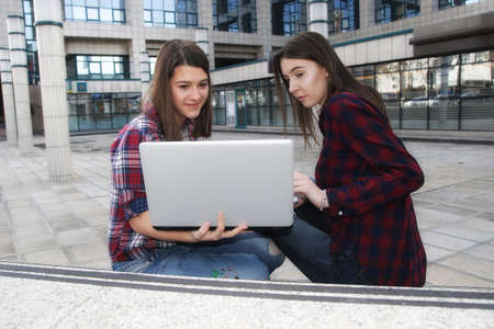 Two girl students with laptop learning outdoors in the campusの写真素材