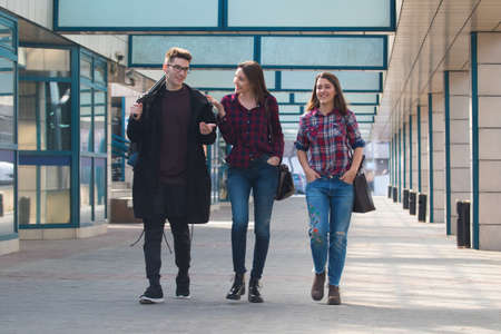 Three students walking and smiling in the campusの写真素材