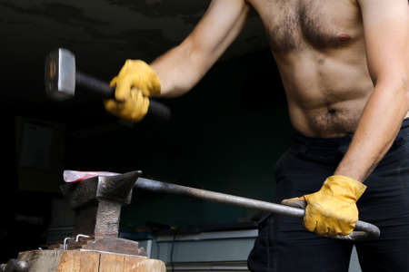 Blacksmith mint hot steel with hammer on the anvil