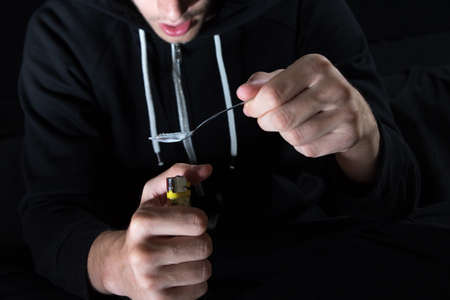 The young drug  addict prepares heroin with spoon and lighterの写真素材
