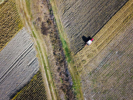 Aerial view of red Tractor harrowing soilの写真素材