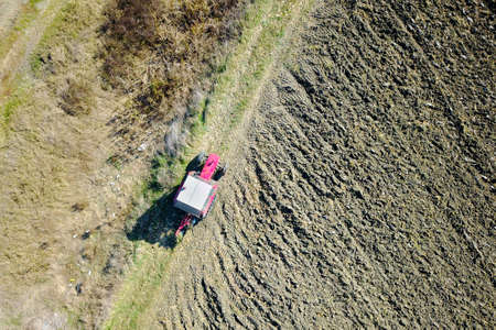 Aerial view of old red Tractor harrowing soil
