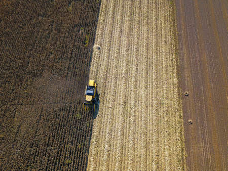 Aerial view of yellow combine harvesting on corn field
