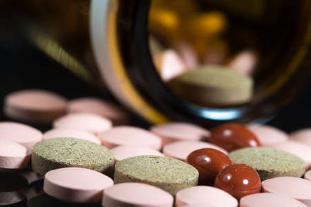 Close up of  painkiller tablets and brown boottle on black