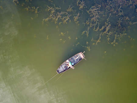 Air view of  fisherman in boat on the green lakeの写真素材