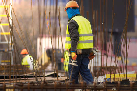 Builder in orange helmet transfers the reinforcement at the construction siteの写真素材