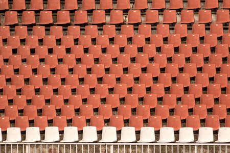 Orange empty stadium chairs and one white row seats in arenaの写真素材
