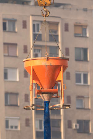 Crane lifting orange concrete tankat the reconstruction area