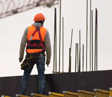 Climber  in orange with hammer at the scaffoldingの写真素材