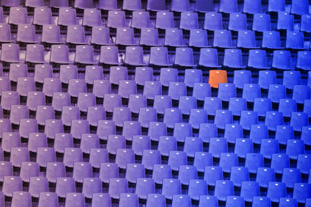 Blue to purple color gradient of empty stadium seats and one redの写真素材