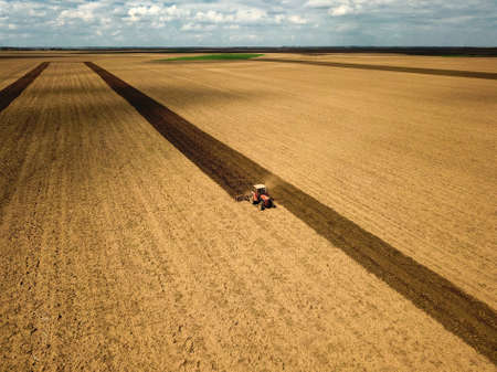 Red tractor plow the field Air view の写真素材
