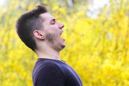 Bearded boy with polen allergy  is sneezing in the parkの写真素材