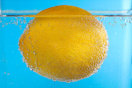 Fresh Lemon in Bubbly Water on blue background