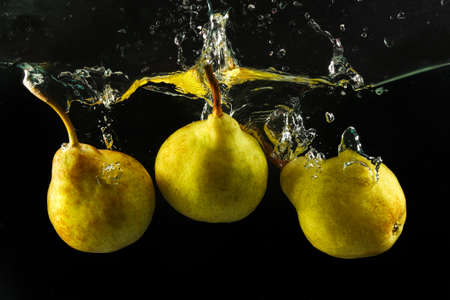  Close up of three pears splashing in water on blackの写真素材