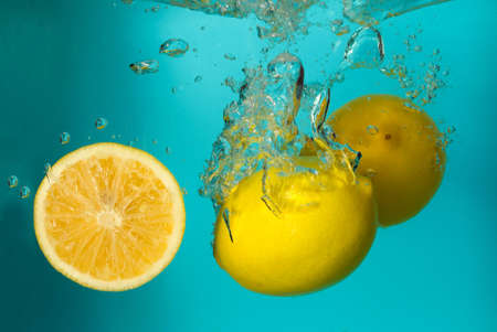 Three lemons spash in water on blue background