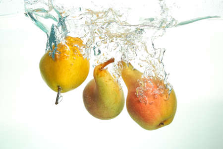 Close up of three pears splashing in water on whiteの写真素材