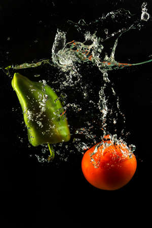 Vegetables tomato and paprika in water splash on black backgroundの写真素材