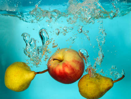 Two pears and apple splash of water on blue bckgroundの写真素材