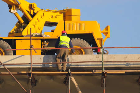 Worker in yellow and crane at the construction siteの写真素材