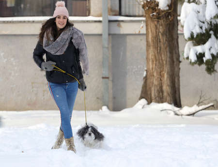 A smiling girl walking whit shih-tzu dog