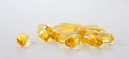 Yellow fish oil capsules, omega 3, on white background