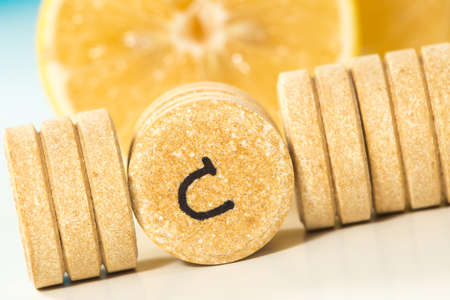 Bunch of vitamin c pills and lemon slice on white