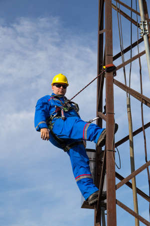 Electrician with safety belt working on electric power pole