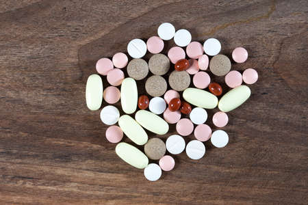 Group of colorful pills and tablets on wooden tableの写真素材