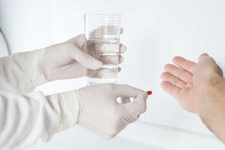 The paramedic administers the antibiotic and glass of water to the patient