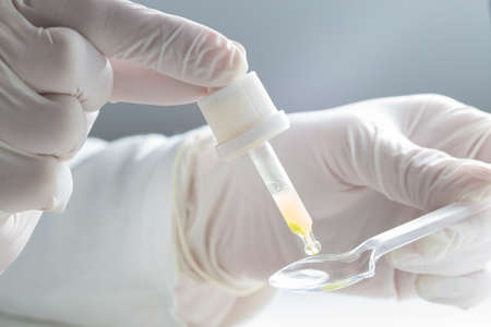 Medic make a syrup dose with pipette and spoonの写真素材