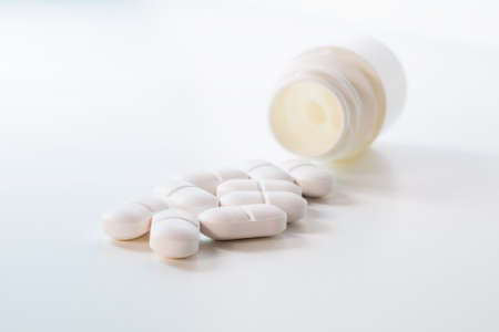 Heap of white tablets and plastic bottle on whiteの写真素材