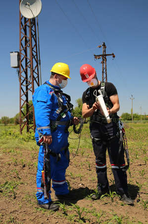 Two workers with protective equipment and masks install a telecommunications system