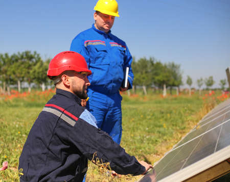 Green energy, two technicians control solar panelsの写真素材