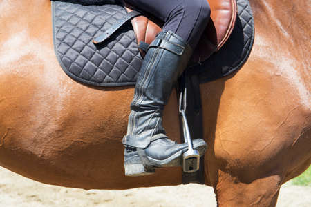 Girl in a saddle with black boots on sorrel horse
