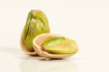 Close up of two roasted peeled salted pistachio nut in shell on white background