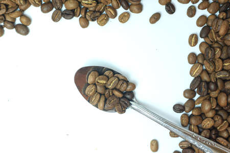 Coffee beans in a spoon on a white background with space for textの写真素材
