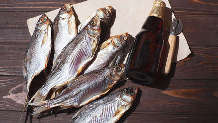 dry fish and a bottle of cold beer on a brown background. mens foodの写真素材
