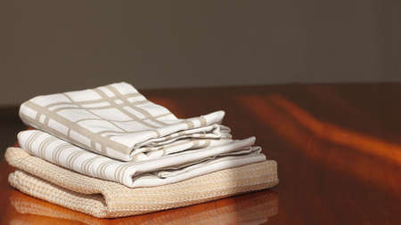 Cotton and linen kitchen textiles - napkins, towels on a wooden table, horizontal, space for text