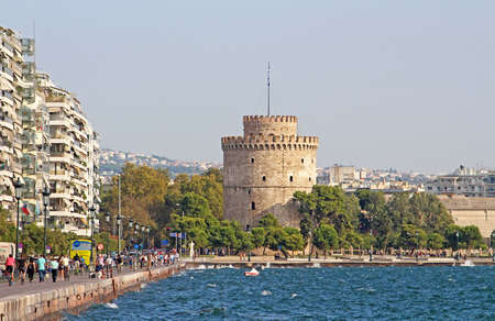 White Tower and unidentified people are walking on the embankment in a storm in Thessaloniki, Greeceのeditorial素材