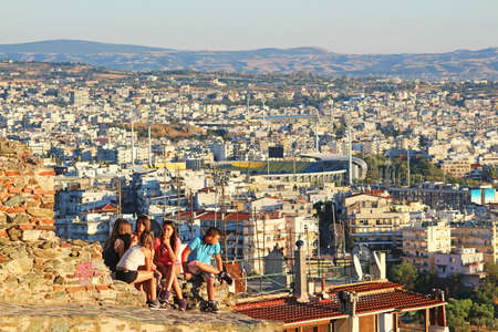 Teenagers are sitting on old byzantine walls at Thessaloniki city in the evening, Greeceのeditorial素材