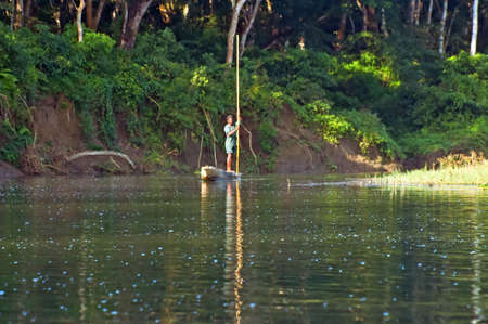 CHITWAN, NEPAL - OCTOBER 15, 2008: Local man traveling by rowboat at wild river in Chitwan National Park Nepal. Park was established in 1973 and granted the status of a World Heritage Site in 1984のeditorial素材